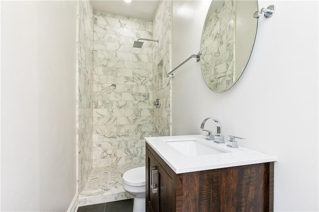 bathroom with tiled shower, vanity, toilet, and tile patterned flooring