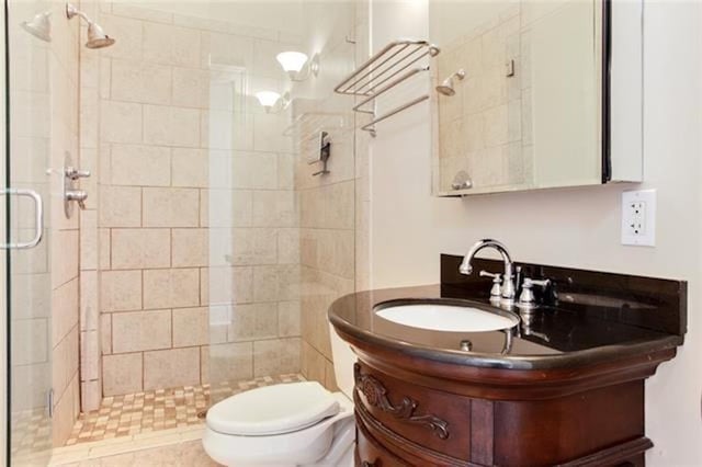 bathroom with walk in shower, vanity, tile patterned floors, and toilet