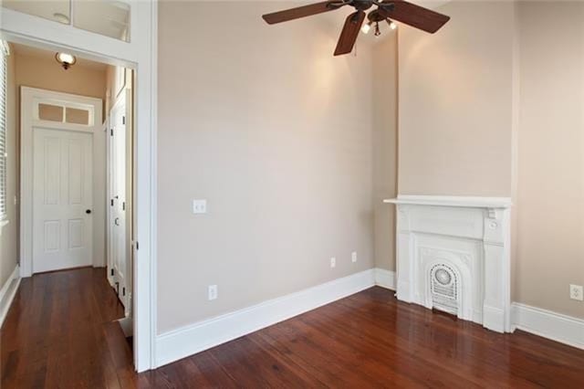 unfurnished living room featuring dark wood-type flooring and ceiling fan