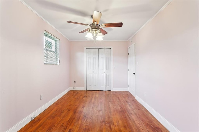 unfurnished bedroom with hardwood / wood-style flooring, ceiling fan, crown molding, and a closet