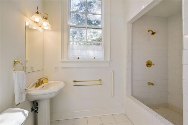 bathroom with tile patterned flooring, a tile shower, and sink