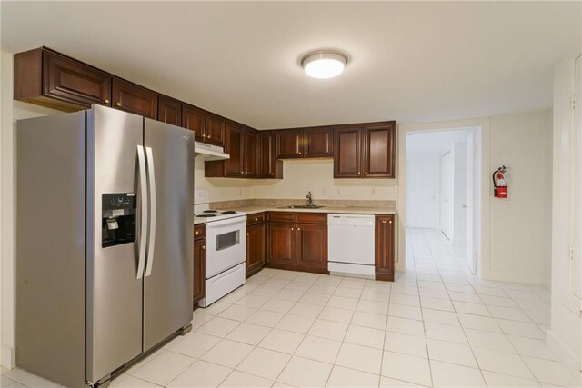 kitchen featuring sink, light tile patterned floors, and white appliances