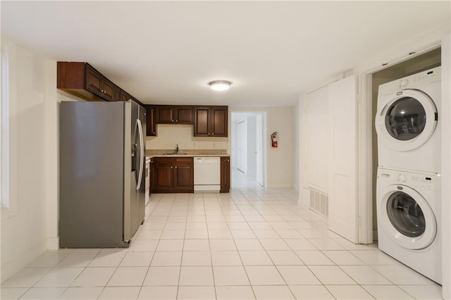 kitchen featuring white dishwasher, stacked washer / drying machine, stainless steel fridge, and dark brown cabinetry