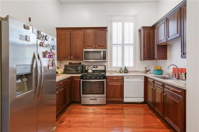 kitchen featuring wood-type flooring, stainless steel appliances, and sink