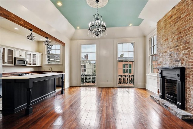 unfurnished living room featuring plenty of natural light, a notable chandelier, and dark hardwood / wood-style flooring