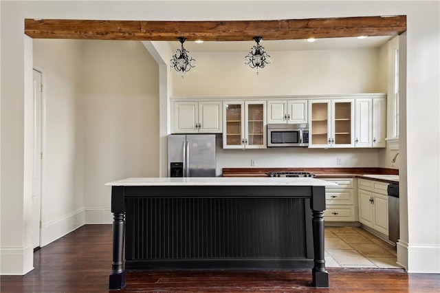 kitchen with sink, stainless steel appliances, wood-type flooring, a kitchen island, and beamed ceiling