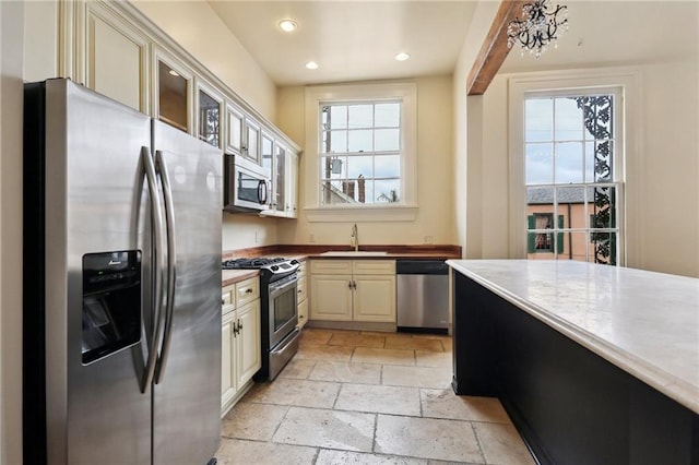 kitchen with appliances with stainless steel finishes, sink, and cream cabinetry