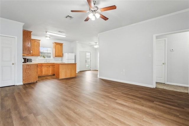 unfurnished living room featuring wood-type flooring, crown molding, and sink