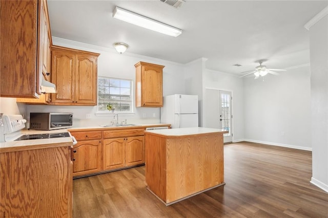 kitchen with a center island, sink, white fridge, light wood-type flooring, and ornamental molding