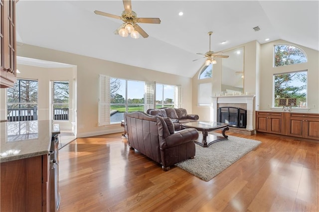 living room featuring ceiling fan, light hardwood / wood-style flooring, and vaulted ceiling