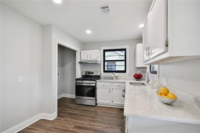 kitchen with sink, stainless steel gas stove, light stone countertops, dark hardwood / wood-style flooring, and white cabinetry