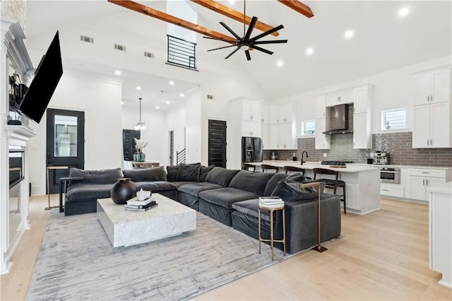 living room featuring ceiling fan, light wood-type flooring, sink, and high vaulted ceiling