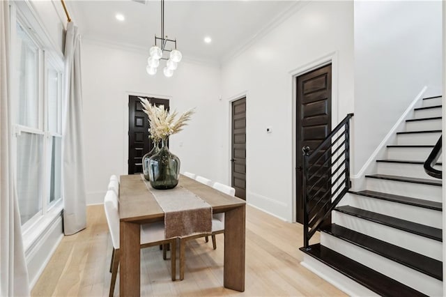 dining space featuring light wood-type flooring, crown molding, and an inviting chandelier