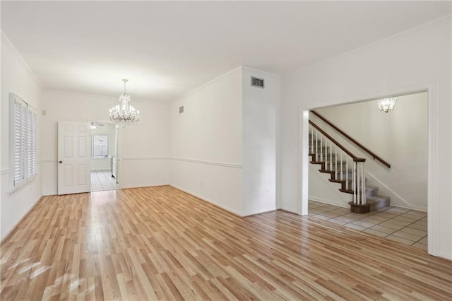 empty room featuring light hardwood / wood-style floors, crown molding, and an inviting chandelier