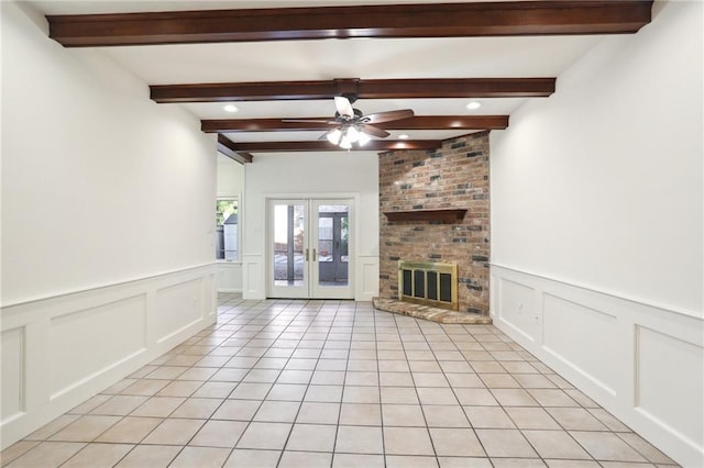 unfurnished living room featuring beam ceiling, a fireplace, ceiling fan, and french doors