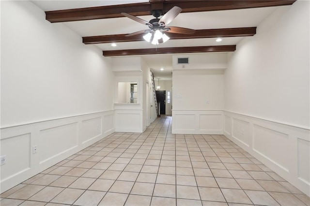 empty room featuring ceiling fan, beam ceiling, and light tile patterned flooring