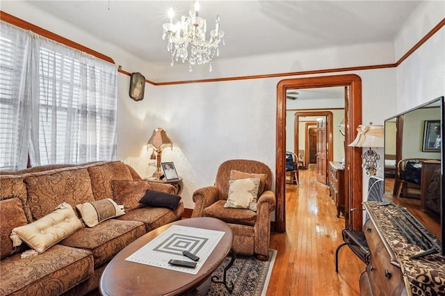 living room with a wealth of natural light, light wood-type flooring, and a notable chandelier