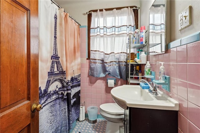 bathroom featuring tile patterned floors, vanity, toilet, and tile walls