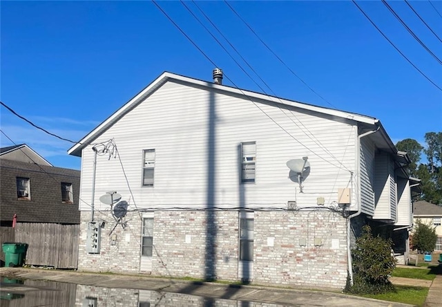 view of side of home with fence and brick siding