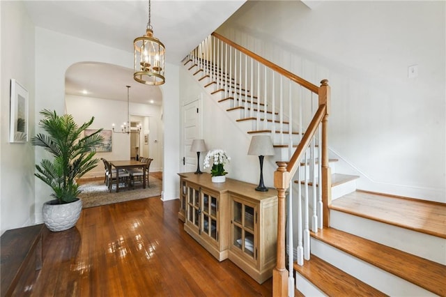 staircase with hardwood / wood-style flooring and a notable chandelier