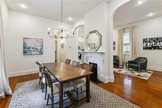 dining space featuring a notable chandelier, dark wood-type flooring, and a high end fireplace