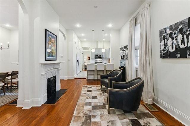 living room with hardwood / wood-style floors, a high end fireplace, and a chandelier