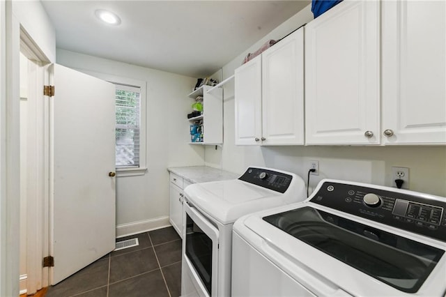 clothes washing area with dark tile patterned flooring, cabinets, and washing machine and clothes dryer