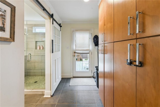 corridor featuring a barn door, crown molding, and dark tile patterned flooring