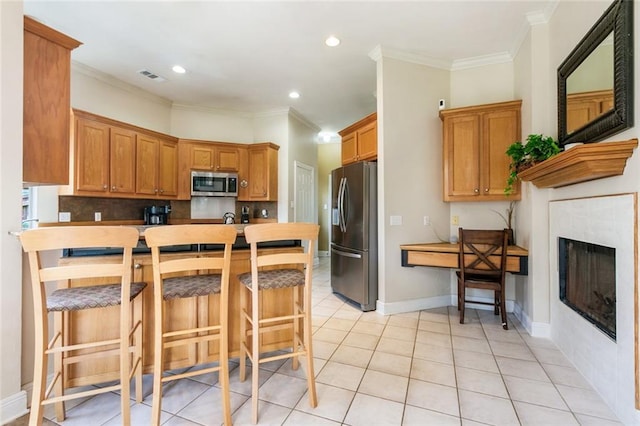 kitchen with a kitchen breakfast bar, kitchen peninsula, appliances with stainless steel finishes, light tile patterned flooring, and ornamental molding