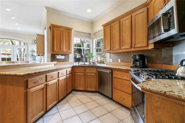 kitchen with kitchen peninsula, appliances with stainless steel finishes, decorative backsplash, light stone counters, and crown molding