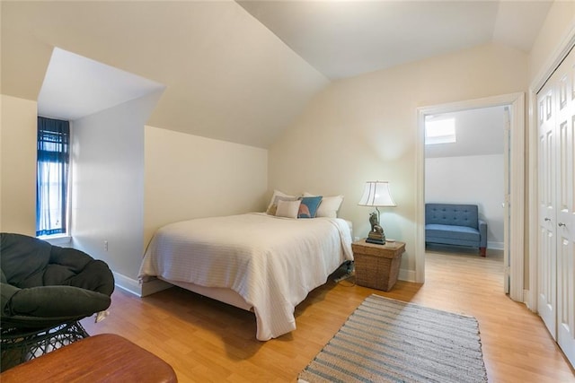 bedroom with vaulted ceiling, light wood-type flooring, and a closet