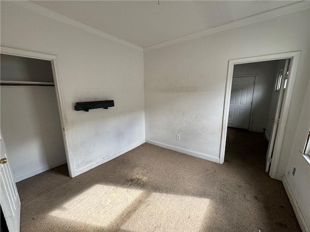 unfurnished bedroom with dark colored carpet, a closet, and crown molding