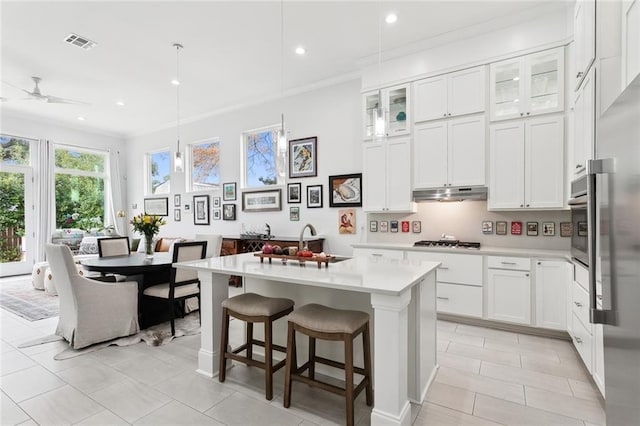 kitchen with stainless steel appliances, white cabinetry, a kitchen island with sink, and ceiling fan