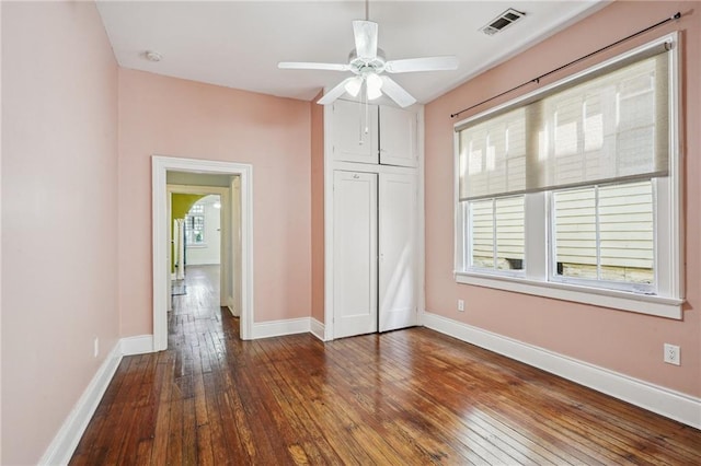 unfurnished bedroom with multiple windows, ceiling fan, and dark hardwood / wood-style flooring