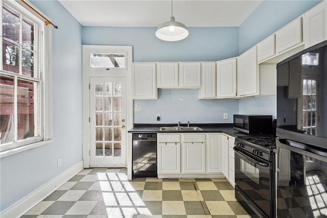 kitchen featuring a healthy amount of sunlight, white cabinetry, black appliances, and decorative light fixtures