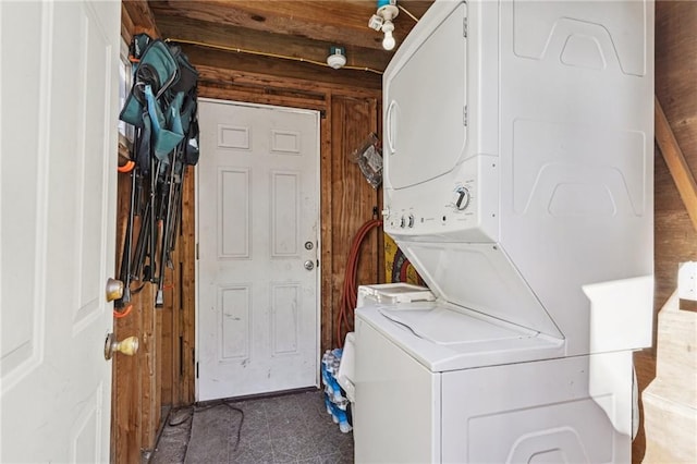 clothes washing area with stacked washer / drying machine and wood walls