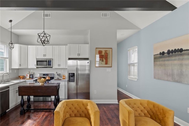 kitchen featuring white cabinetry, decorative light fixtures, vaulted ceiling, and appliances with stainless steel finishes