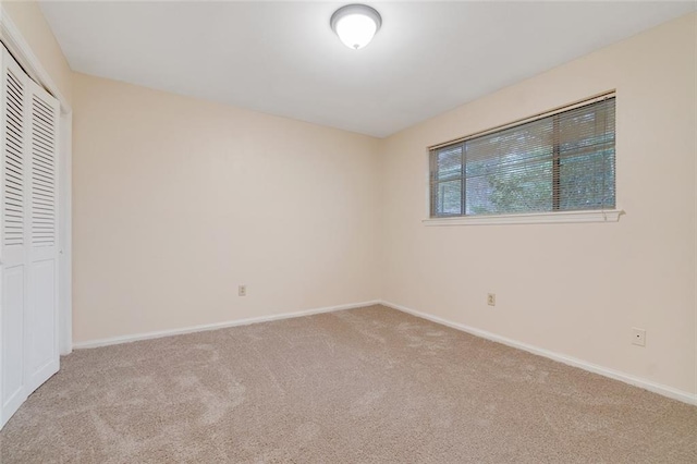 unfurnished bedroom with light carpet and a closet