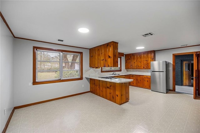 kitchen featuring backsplash, kitchen peninsula, ornamental molding, and stainless steel refrigerator