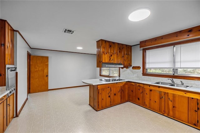 kitchen featuring backsplash, oven, sink, kitchen peninsula, and electric stovetop