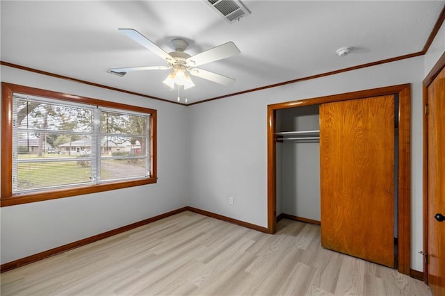 unfurnished bedroom featuring ceiling fan, a closet, ornamental molding, and light wood-type flooring