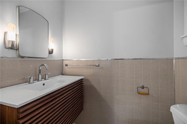 bathroom featuring vanity, toilet, and tile walls