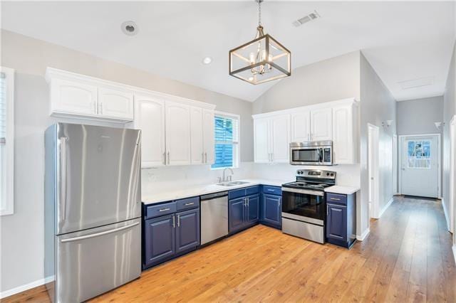 kitchen featuring blue cabinetry, white cabinets, stainless steel appliances, and decorative light fixtures