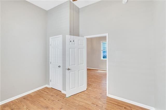 spare room featuring light hardwood / wood-style flooring and a high ceiling