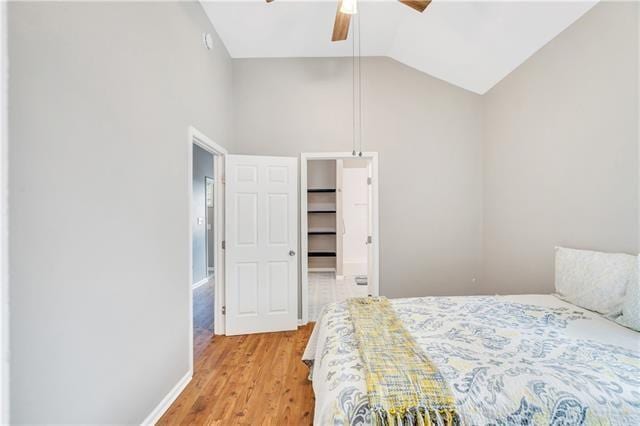 bedroom featuring a walk in closet, ceiling fan, light hardwood / wood-style flooring, and lofted ceiling