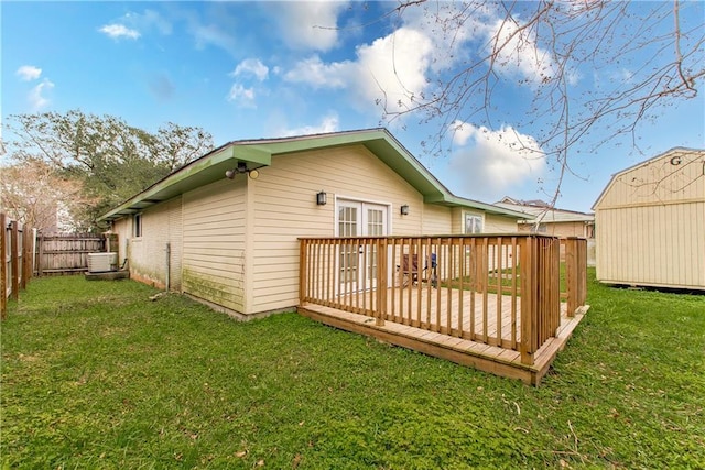 rear view of house with a shed, a yard, and a wooden deck