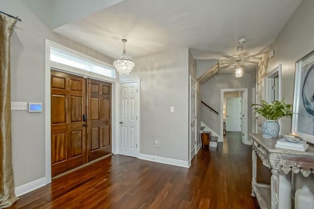 foyer with dark wood-type flooring and an inviting chandelier