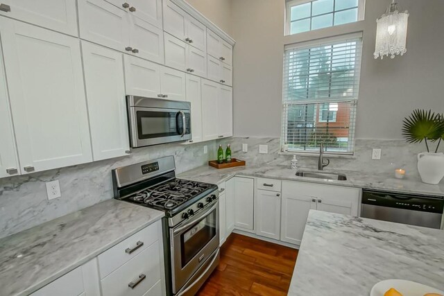 kitchen featuring white cabinetry, decorative light fixtures, sink, dark wood-type flooring, and appliances with stainless steel finishes