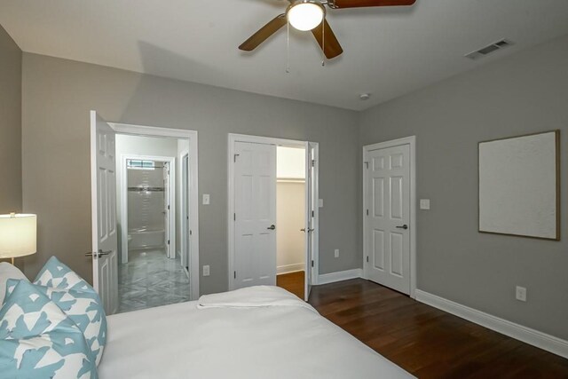 bedroom featuring ceiling fan, dark wood-type flooring, connected bathroom, and a walk in closet