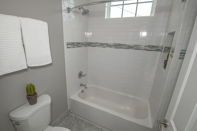 bathroom with toilet and tiled shower / bath combo